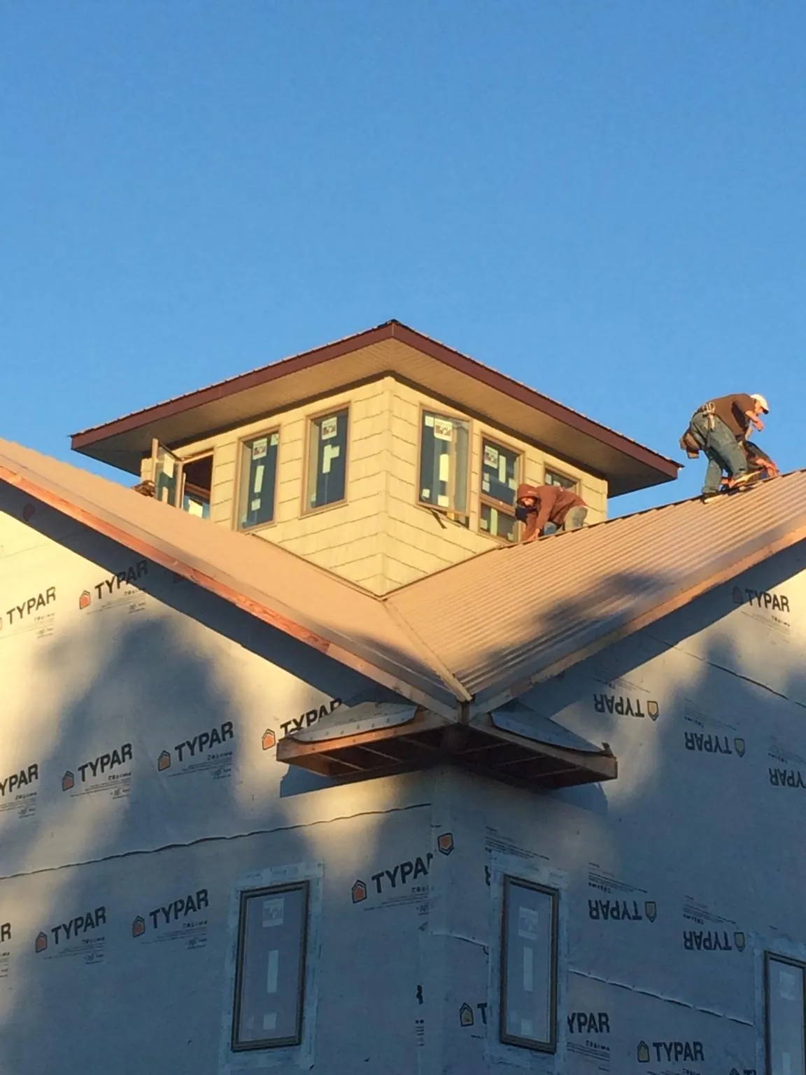 Roofers working around a rooftop cupola on a new metal roof at sunset — Roof Waterproofing in Taylor by Roofing Brothers